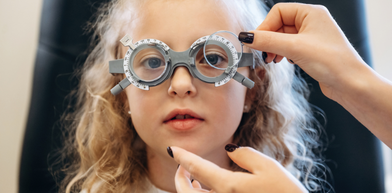 A child having an eye exam using a trial frame and lenses.