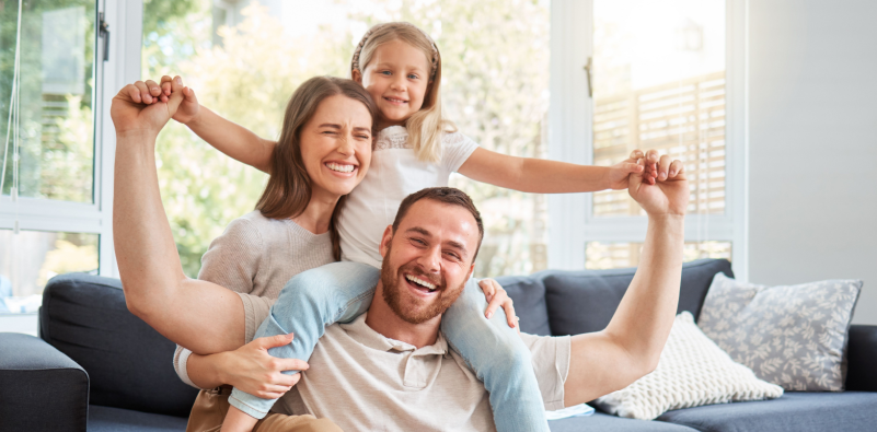 Smiling parents and child at home on their sofa