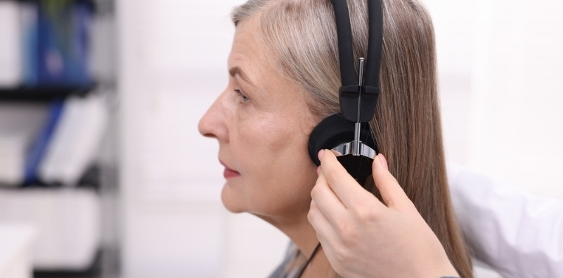 A woman having a pair of headphones placed on her ears during a hearing test