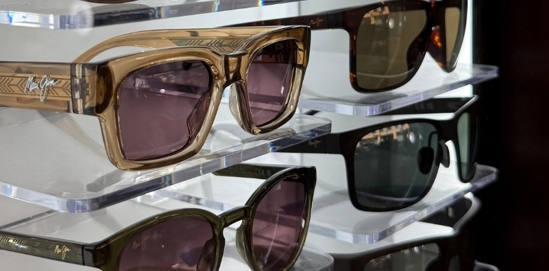An close-up of assorted Maui Jim polarised sunglasses displayed on shelves at The Optical Studio opticians, Pimlico