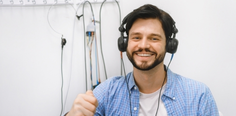 A smiling middle-aged man wearing headphones during a hearing assessment.