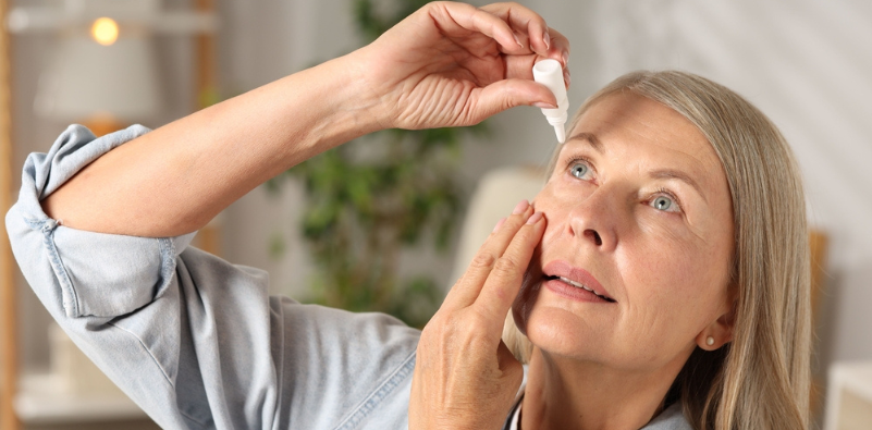 A middle-aged woman putting eye drops in her eye