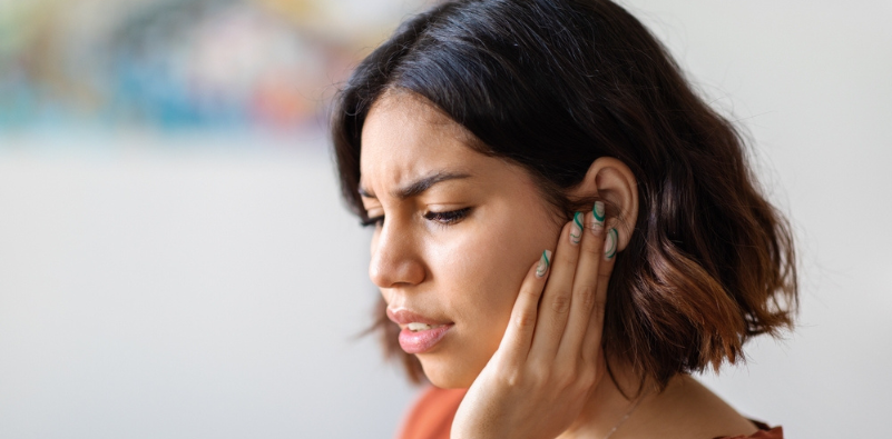 Young woman holding her hand up to her left ear